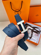 Blue leather belt with silver H buckle and visible pin strap holes.