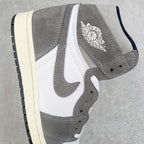 High-top sneaker side view with gray suede, white paneling, and Jordan logo near ankle.