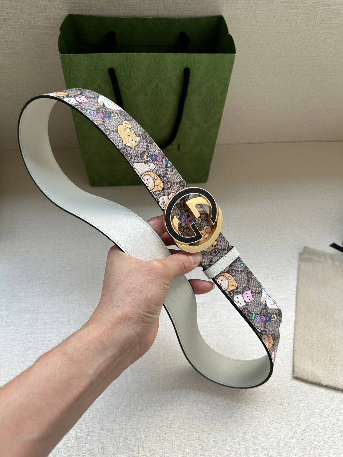 Gucci belt laid out with cartoon print strap and round logo buckle