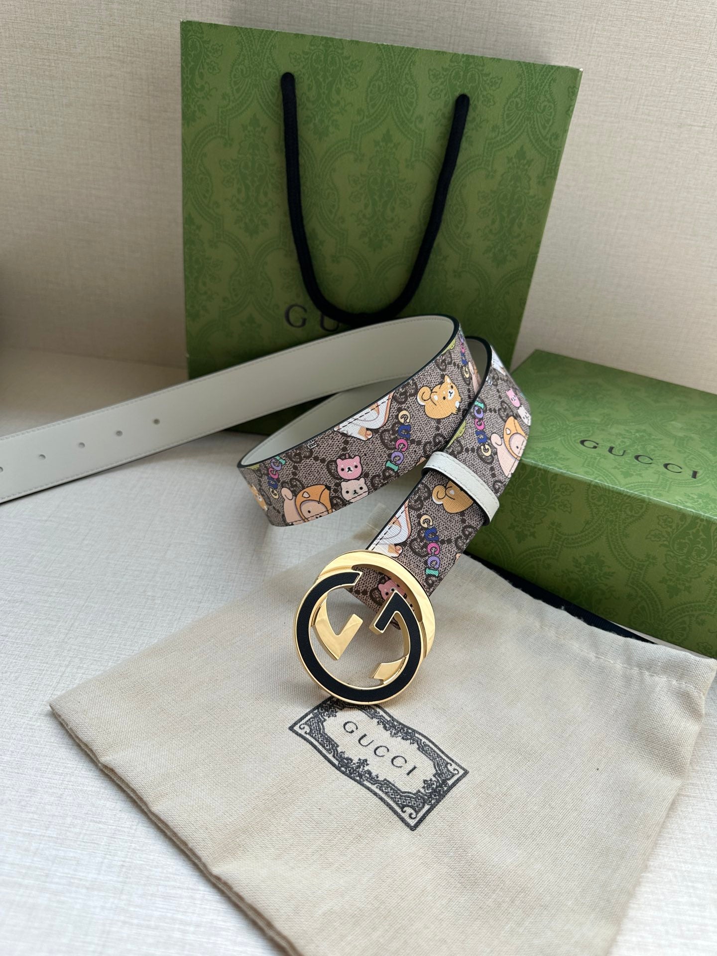 Gucci belt with cartoon print strap and gold-toned round logo buckle on light gray leather