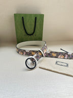 Gucci belt with multicolor cartoon print, round logo buckle, and light gray strap
