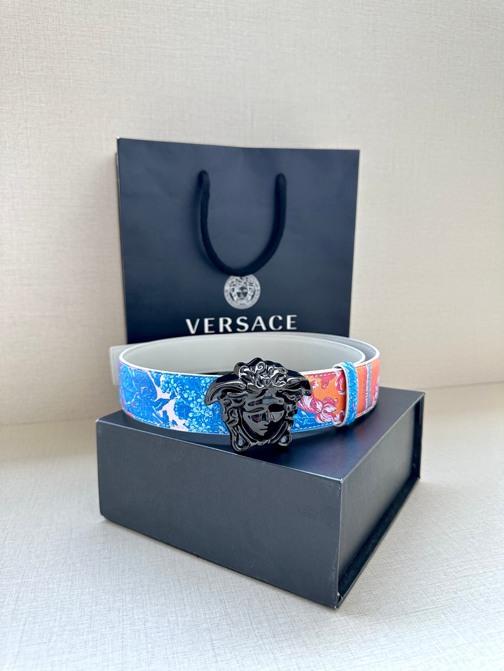 Versace belt with blue and pink floral print and black lion buckle on white strap