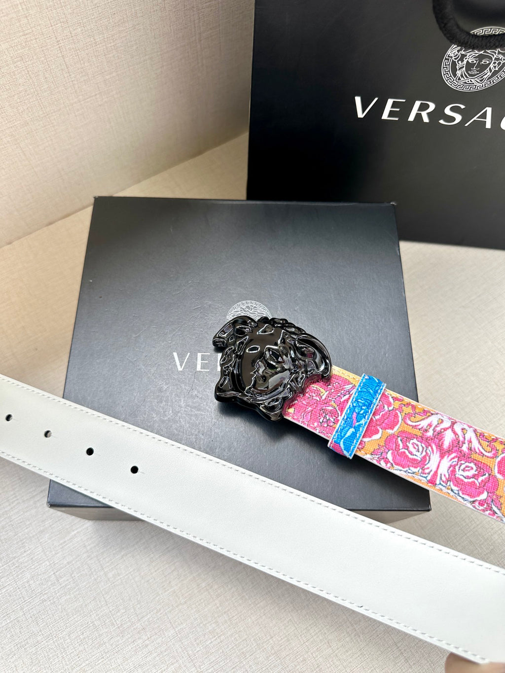 Versace belt with pink and blue floral print and black lion buckle on white strap