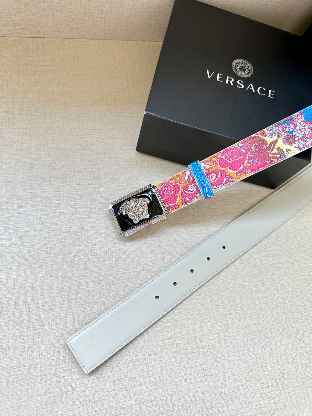 Versace belt with multicolor patterned strap and gold Medusa buckle, on white leather