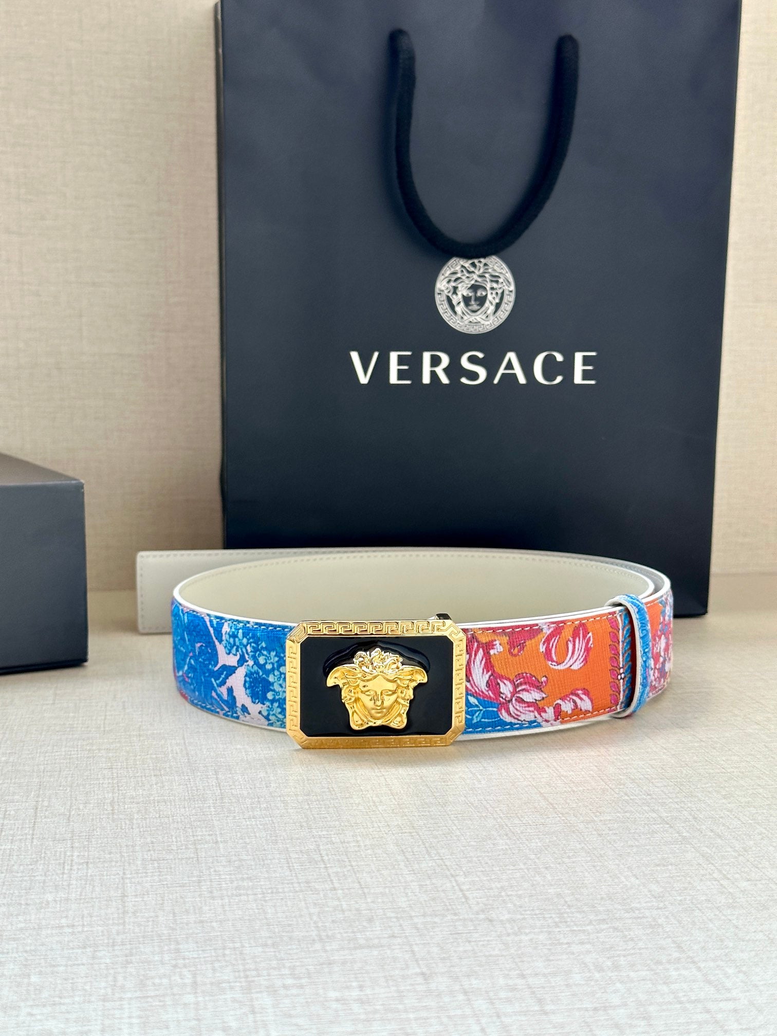 Versace belt on display: multicolor strap with gold Medusa buckle and gold trim