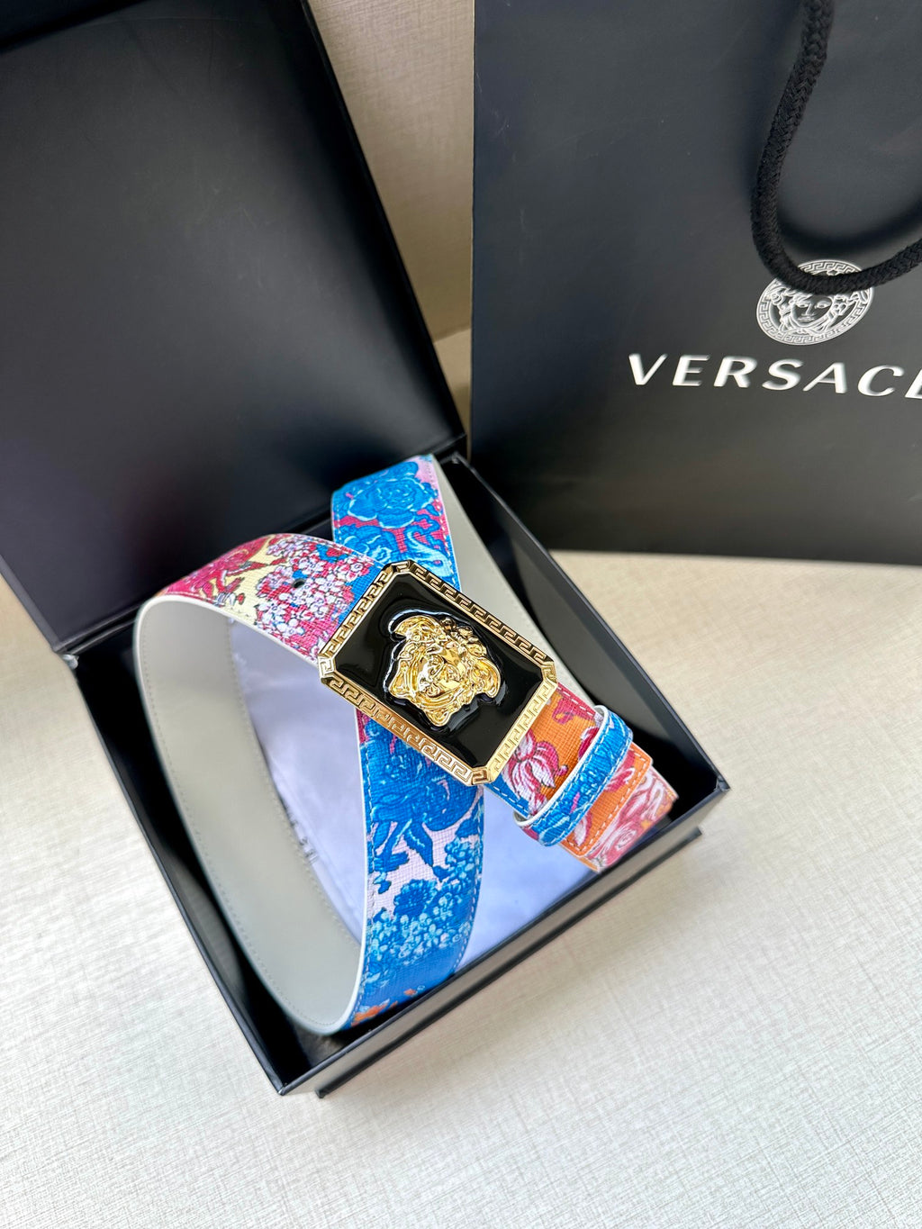 Versace belt detail: patterned pink and blue strap with gold Medusa buckle in box