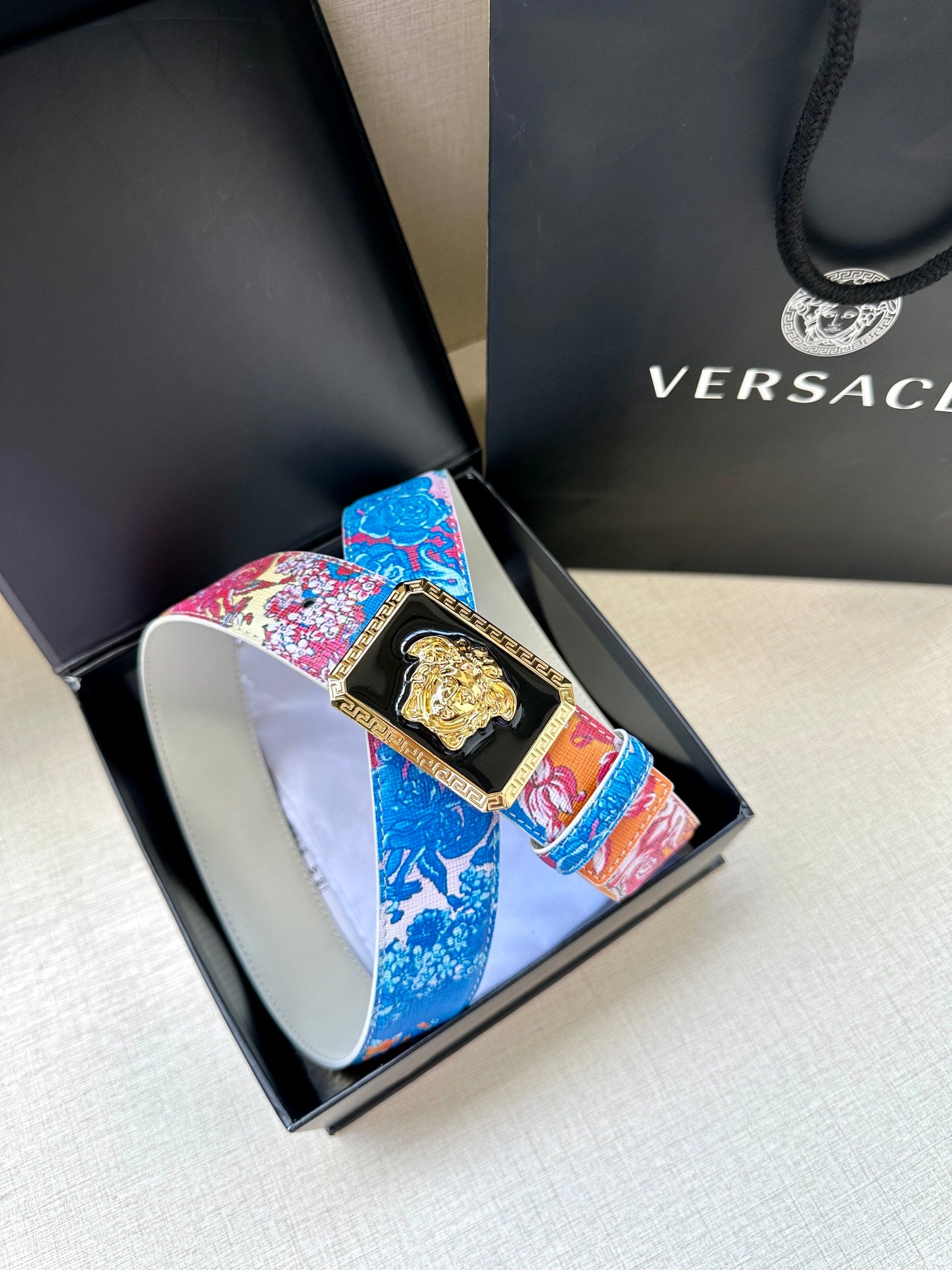 Versace belt detail: patterned pink and blue strap with gold Medusa buckle in box