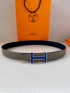 Grey leather belt with blue enamel H buckle, centered on the strap