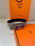 Grey leather belt with gold-tone and blue H buckle, contrast stitched edge