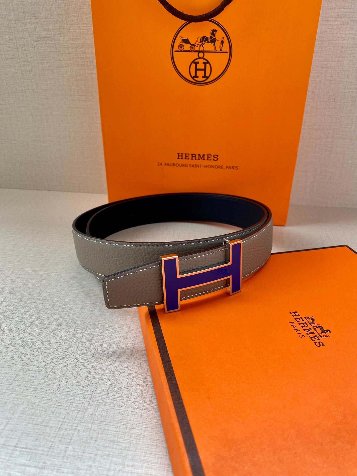 Grey leather belt with gold-tone and blue H buckle, contrast stitched edge