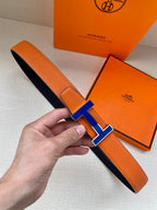Hermes belt in orange leather with blue H buckle and dark underside