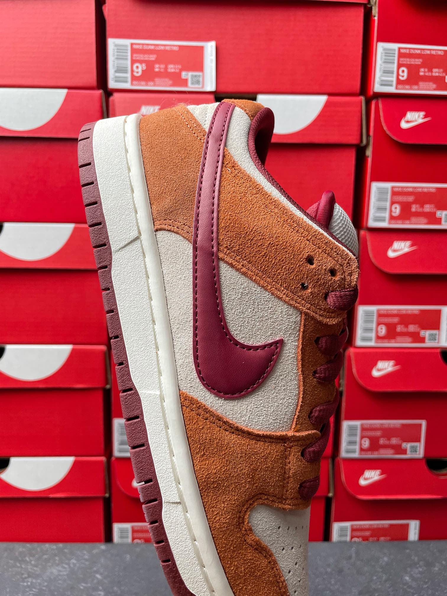 Nike Dunk Low sneaker side view with tan suede, burgundy swoosh, and textured cream midsole
