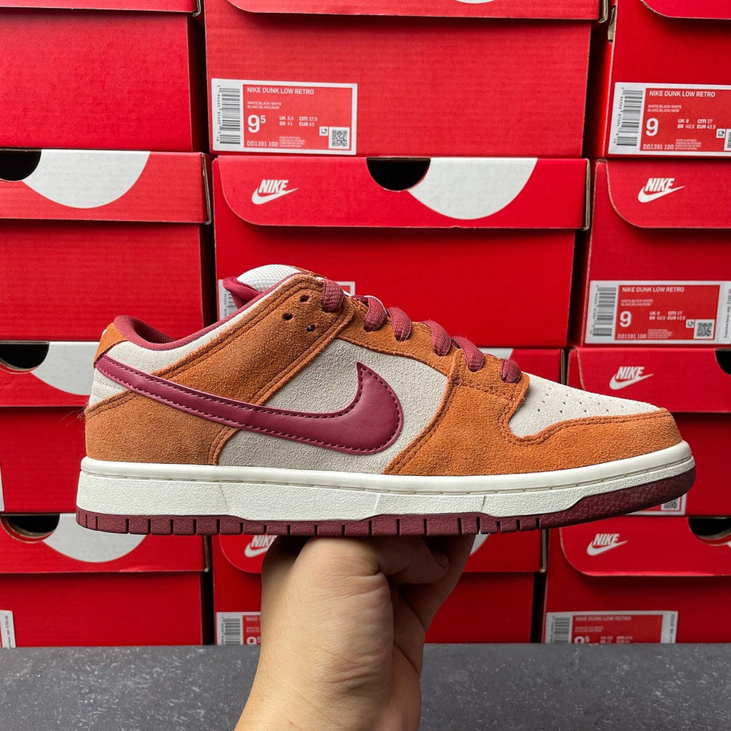 Nike Dunk Low sneaker with tan suede panels, burgundy swoosh, and cream sole
