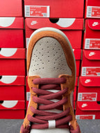 Nike Dunk Low sneaker toe view with tan suede toe, perforations, and burgundy laces