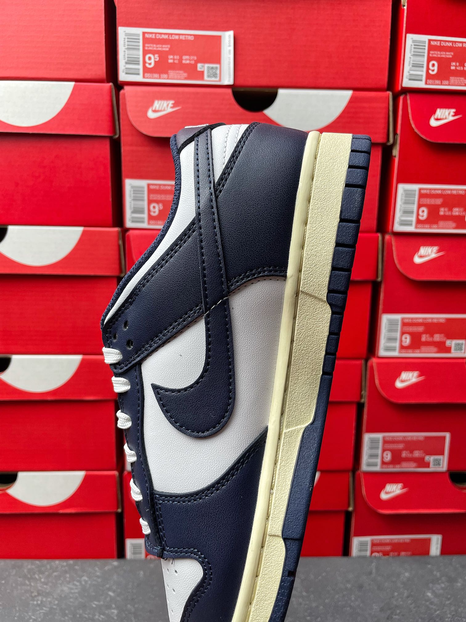 Midnight navy and white low-top sneakers with lace-up front, cream sole edge view