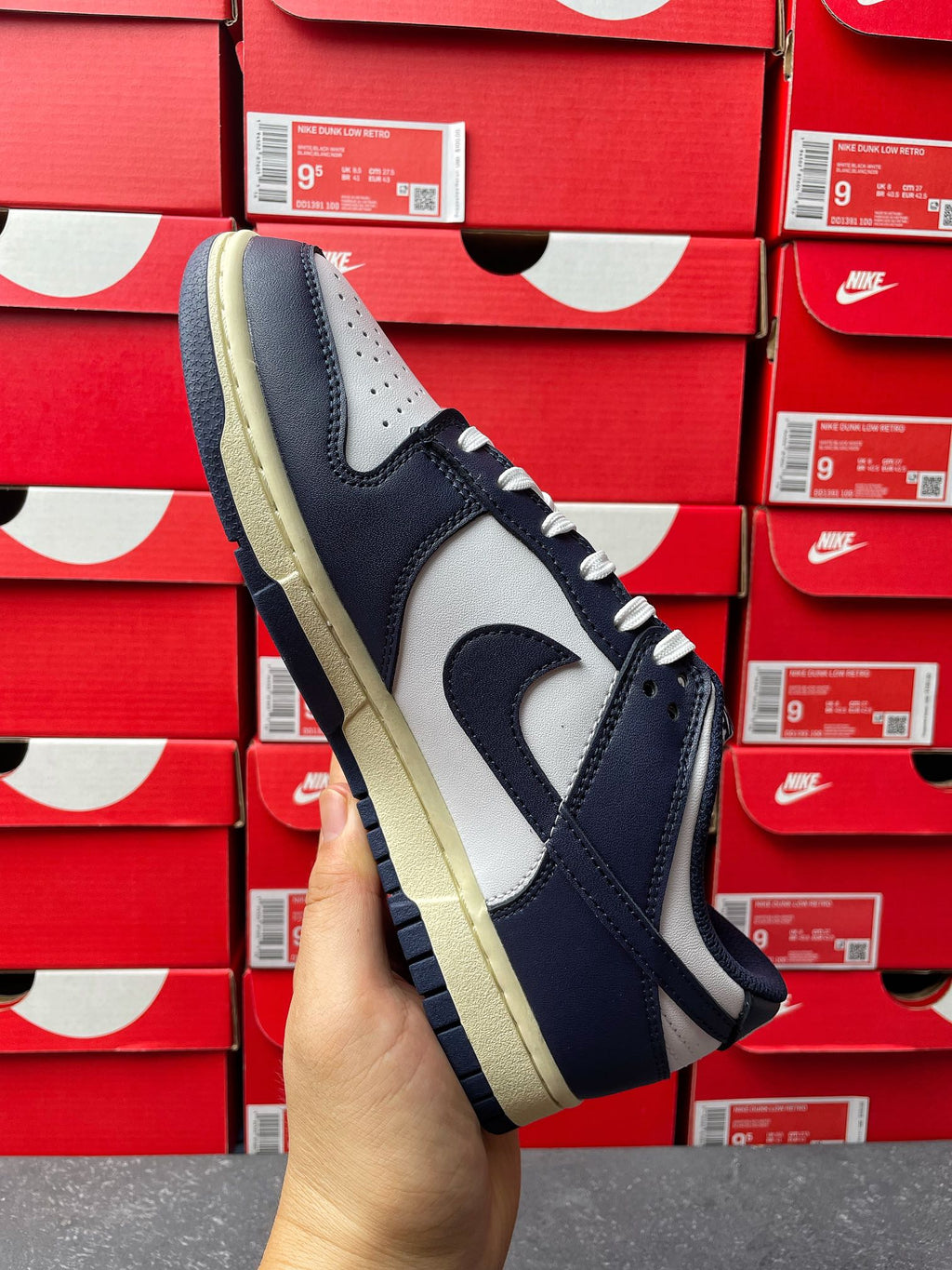 Midnight navy and white low-top sneakers with swoosh and cream outsole, side view