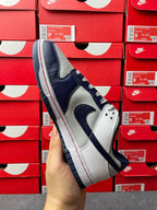 Low-top sneakers, white and navy panels with blue laces, perforated toe and Swoosh.