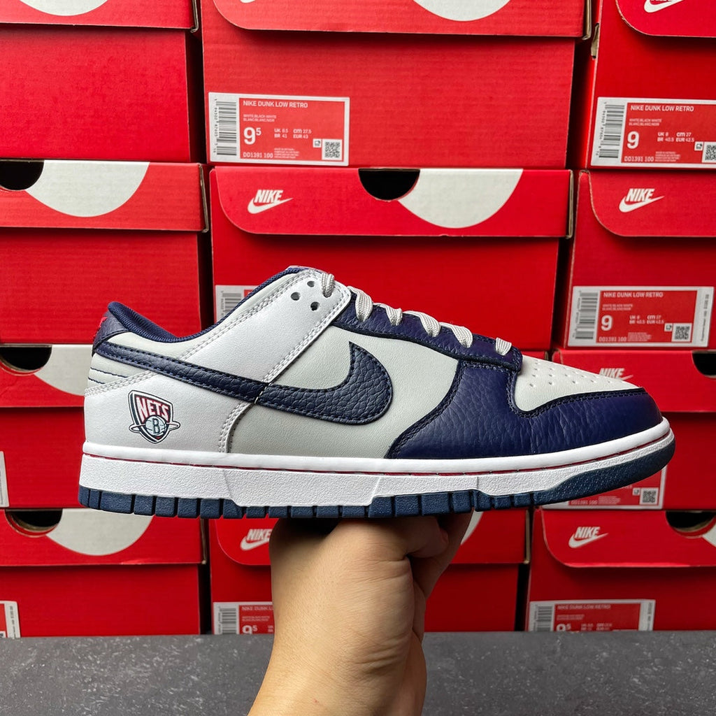 Low-top sneakers with white and navy leather panels, blue Swoosh, lace-up front.