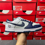Low-top sneakers with white and navy leather panels, blue Swoosh, lace-up front.
