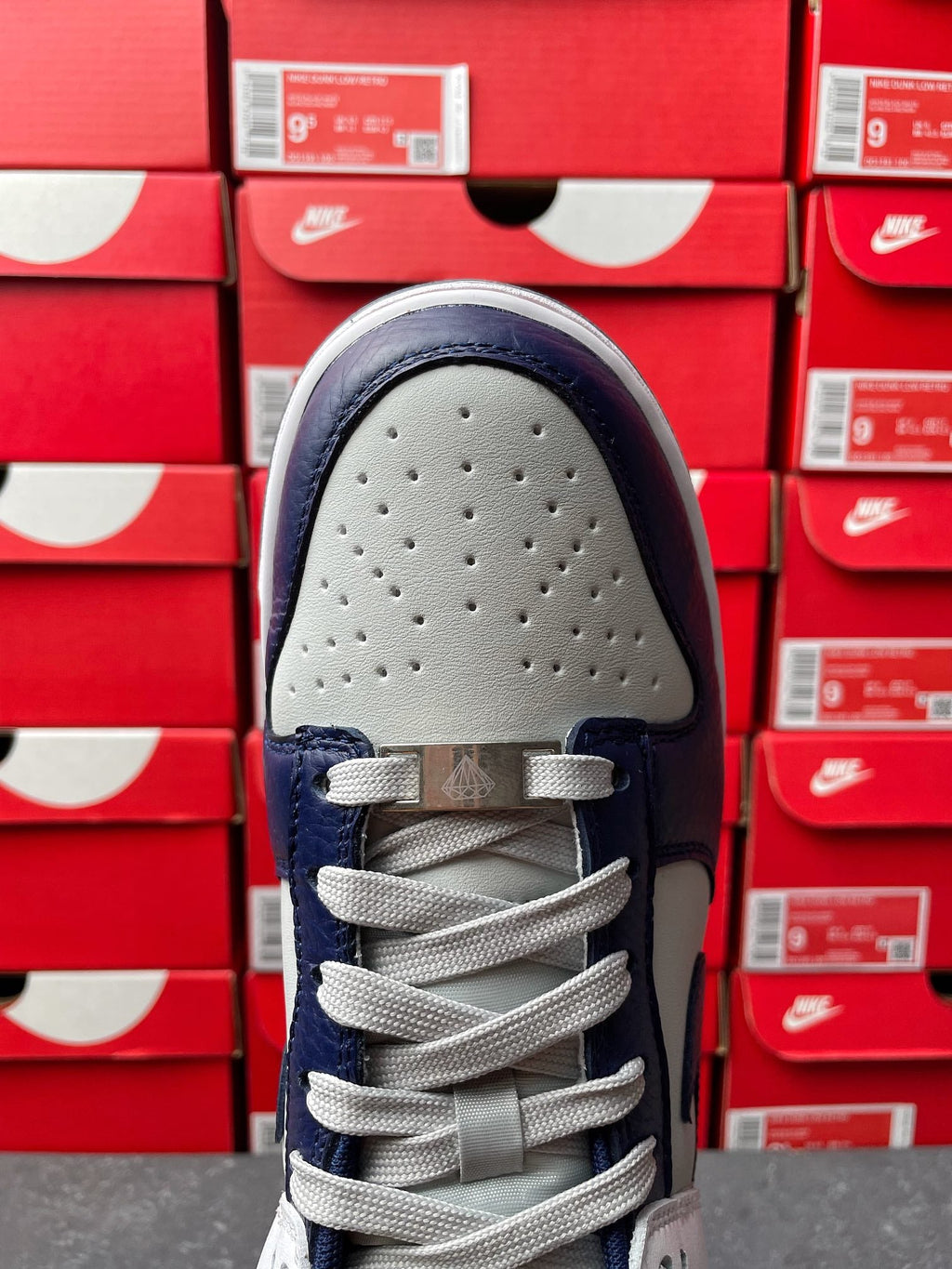 Low-top sneakers, perforated white toe cap with navy eyestays and gray lace-up.
