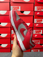 Low-top sneaker angle view with red suede-like upper, gray Swoosh, and white midsole.