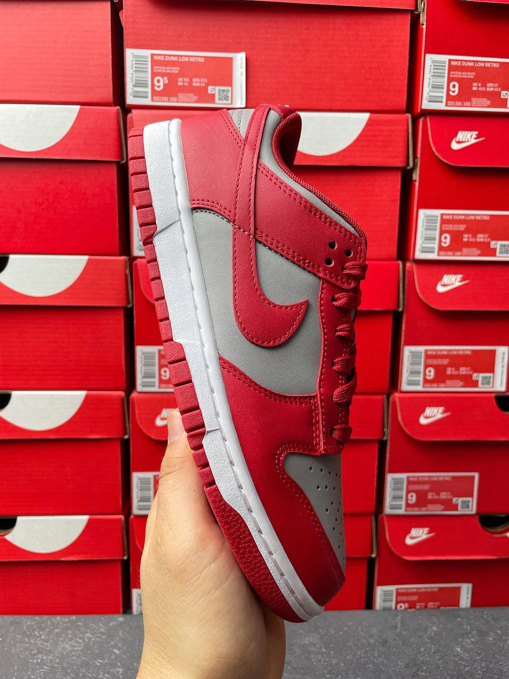 Low-top sneaker side view with red leather upper, gray Swoosh panel, and white sole.