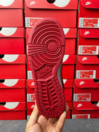 Low-top sneaker outsole view in red with patterned traction tread and Nike text.