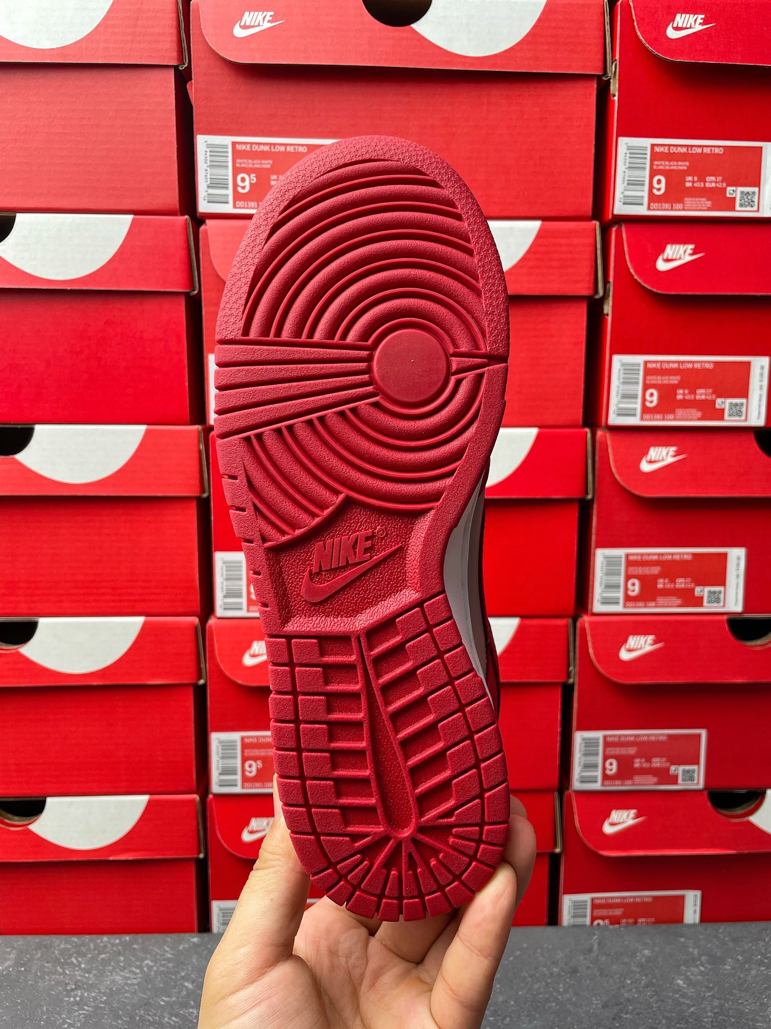Low-top sneaker outsole view in red with patterned traction tread and Nike text.