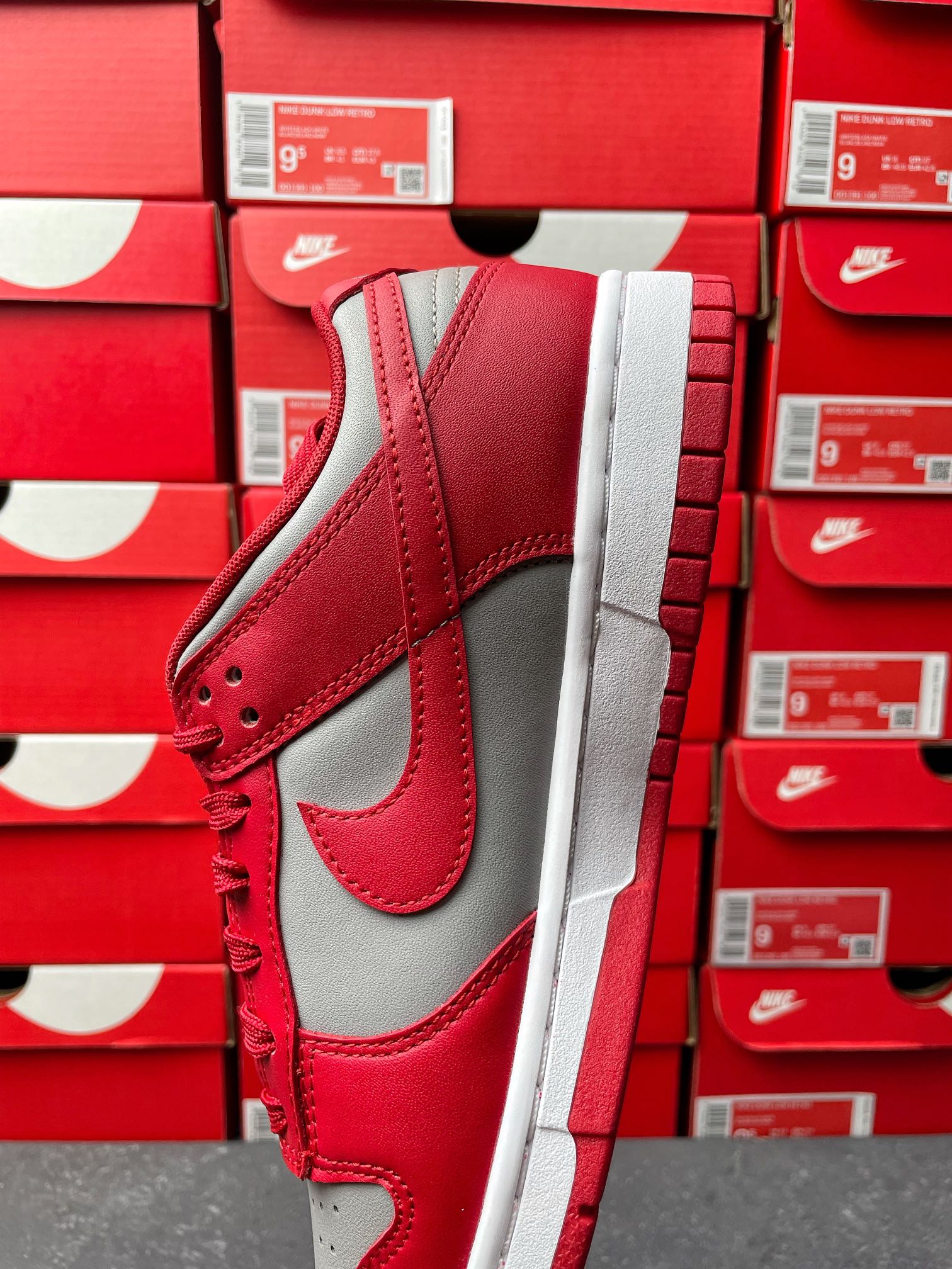 Low-top sneaker quarter view with red upper, gray Swoosh, red laces, and white sole.