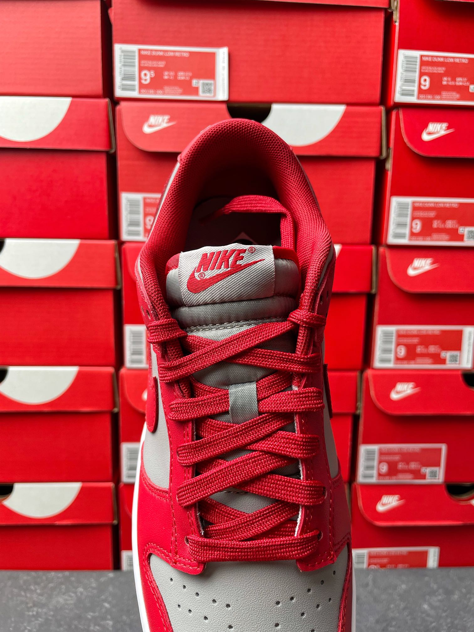 Low-top sneaker showing red tongue and laces with gray collar and Nike logo patch.