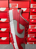 Low-top sneaker with red upper, gray overlays, red lace-up, and white midsole.