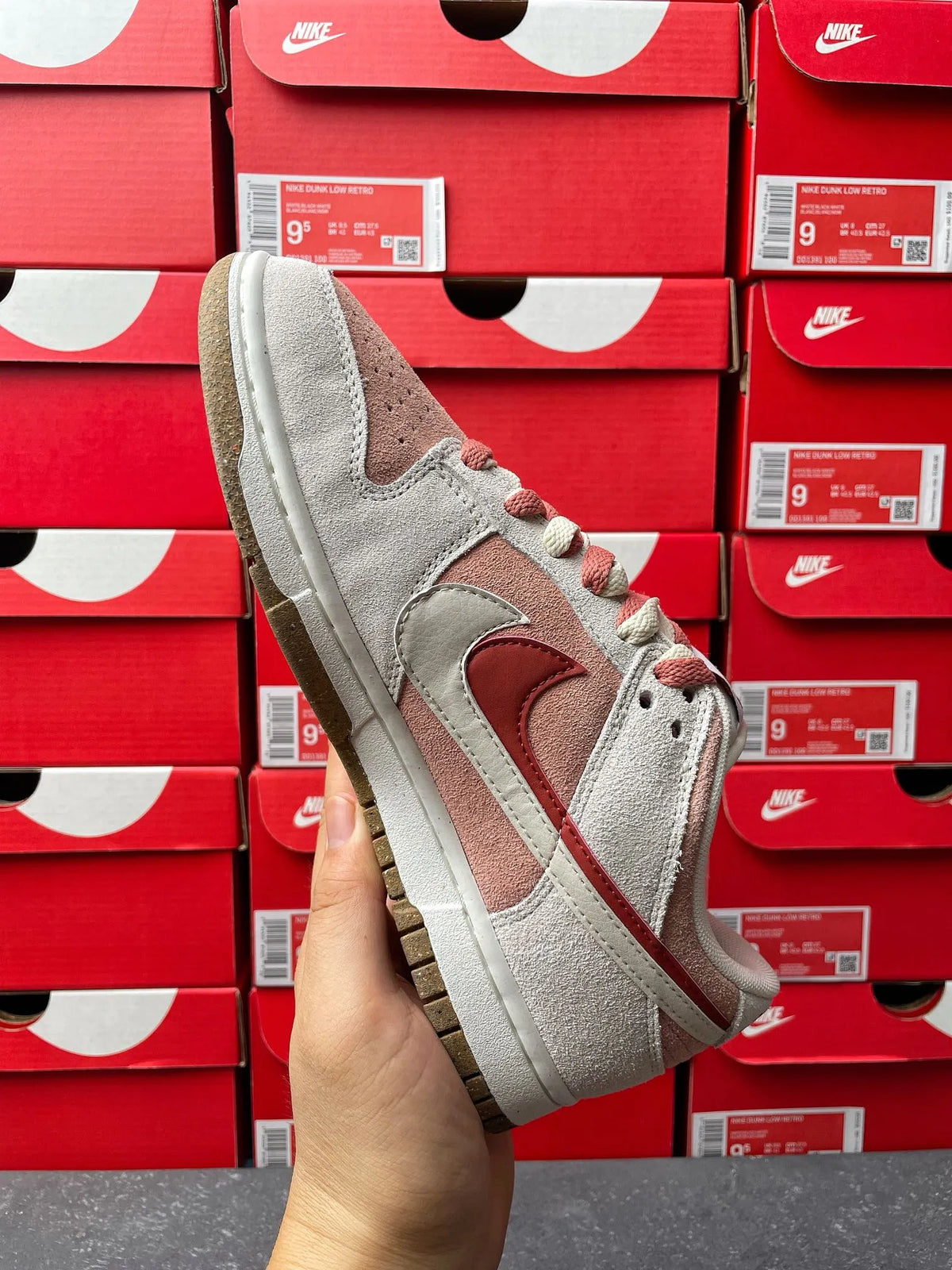 Low-top sneaker side view in light gray suede with brown swoosh and lace trim