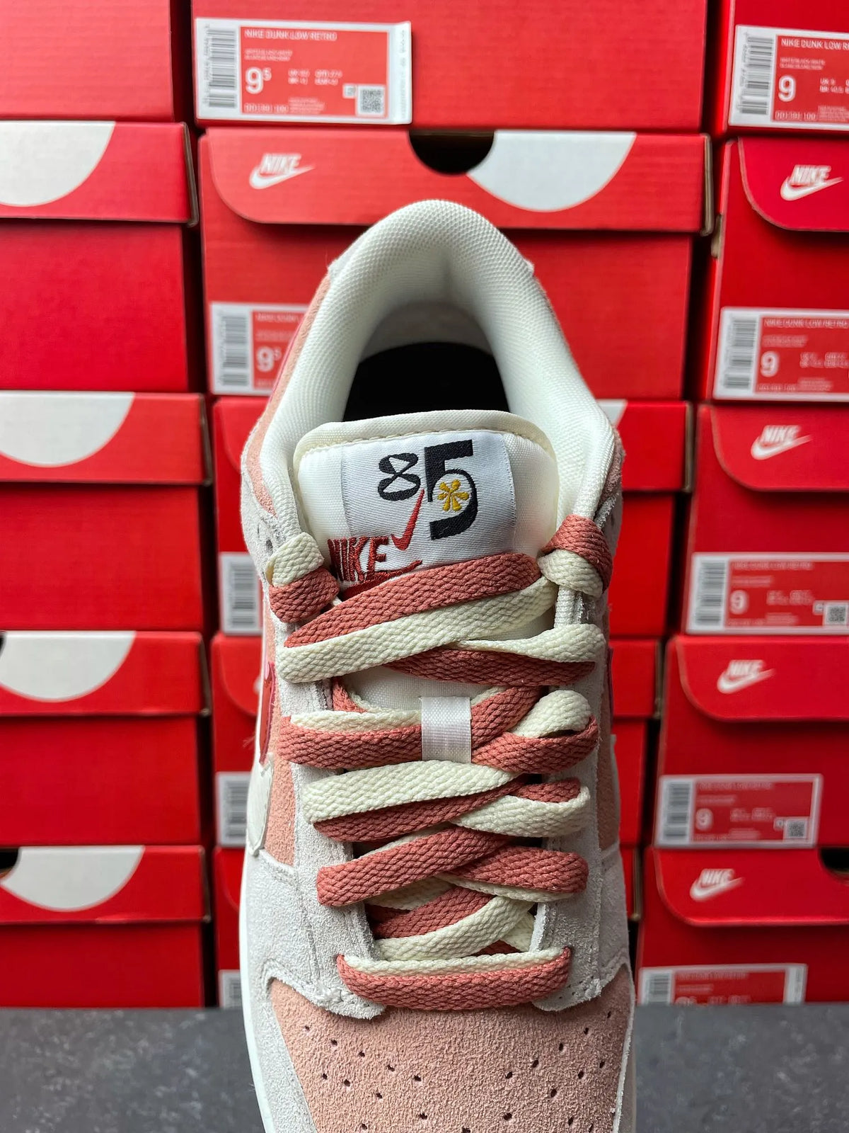 Low-top sneaker with light gray suede upper, pink lace accents, and perforated toe