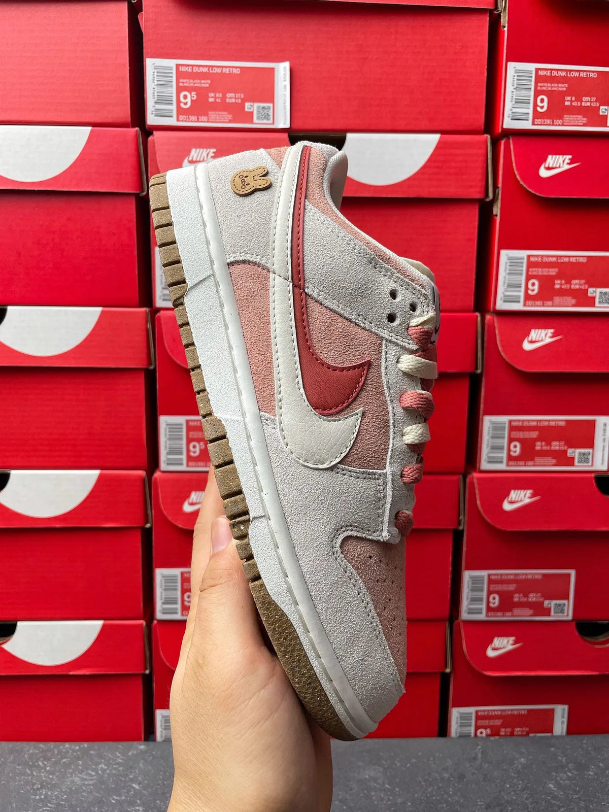 Low-top sneaker quarter view in light gray suede with pink-brown swoosh detail