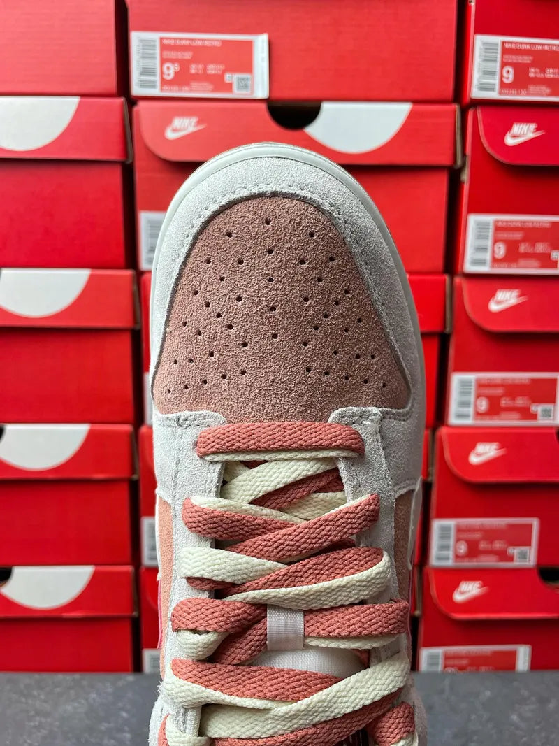 Low-top sneaker toe view with light gray suede, perforations, and pink lace pattern