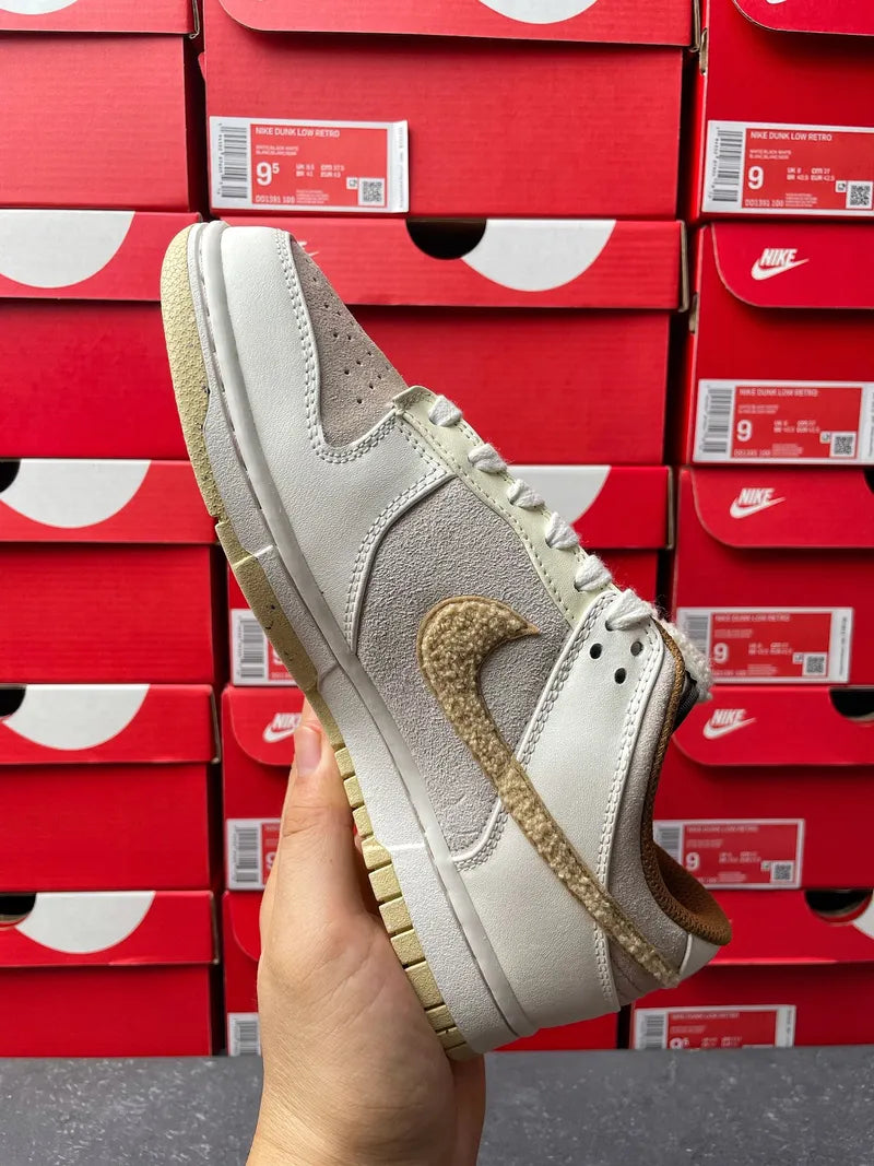 Nike Dunk Low low-top sneaker quarter view, light gray leather with tan lace-panel detail