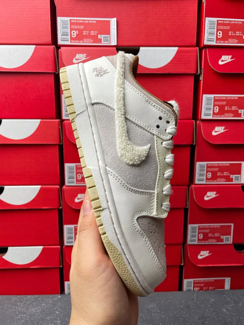 Nike Dunk Low low-top sneaker side view, light gray leather with tan outsole and white laces