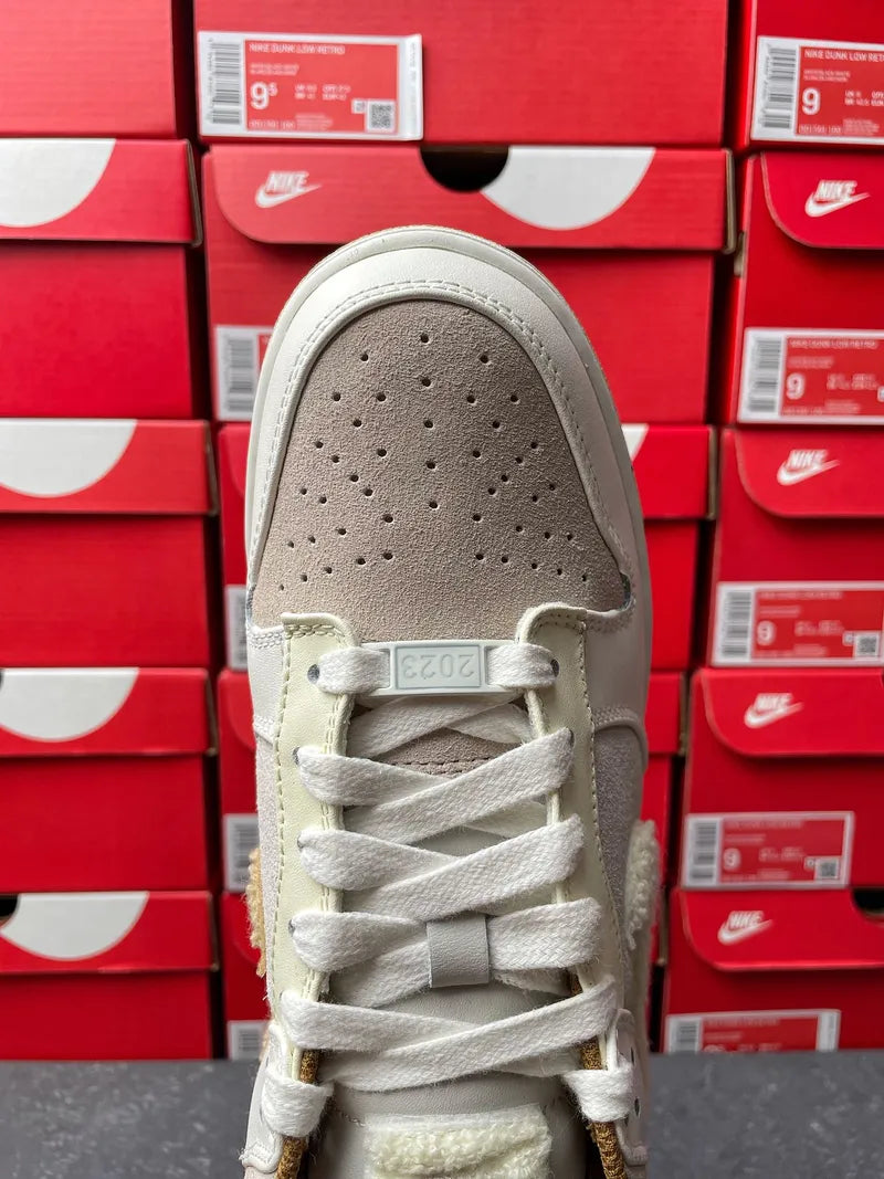 Nike Dunk Low low-top sneaker toe view, perforated light gray leather with white laces