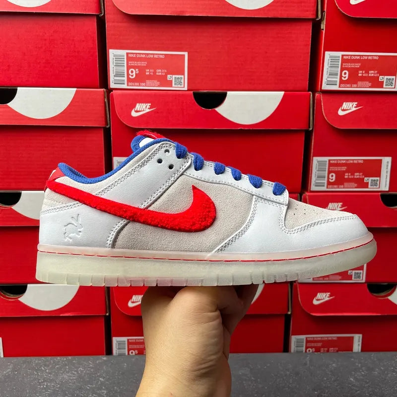 Nike Dunk Low sneakers front view, light gray upper with blue laces and red swoosh.