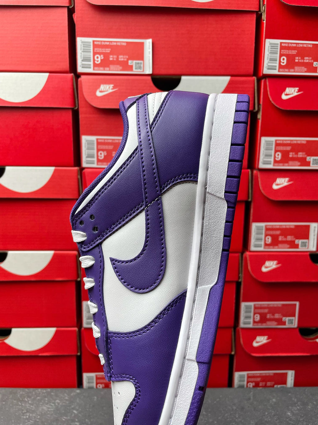 Nike Dunk Low sneaker, angled view with purple leather panels and white midsole