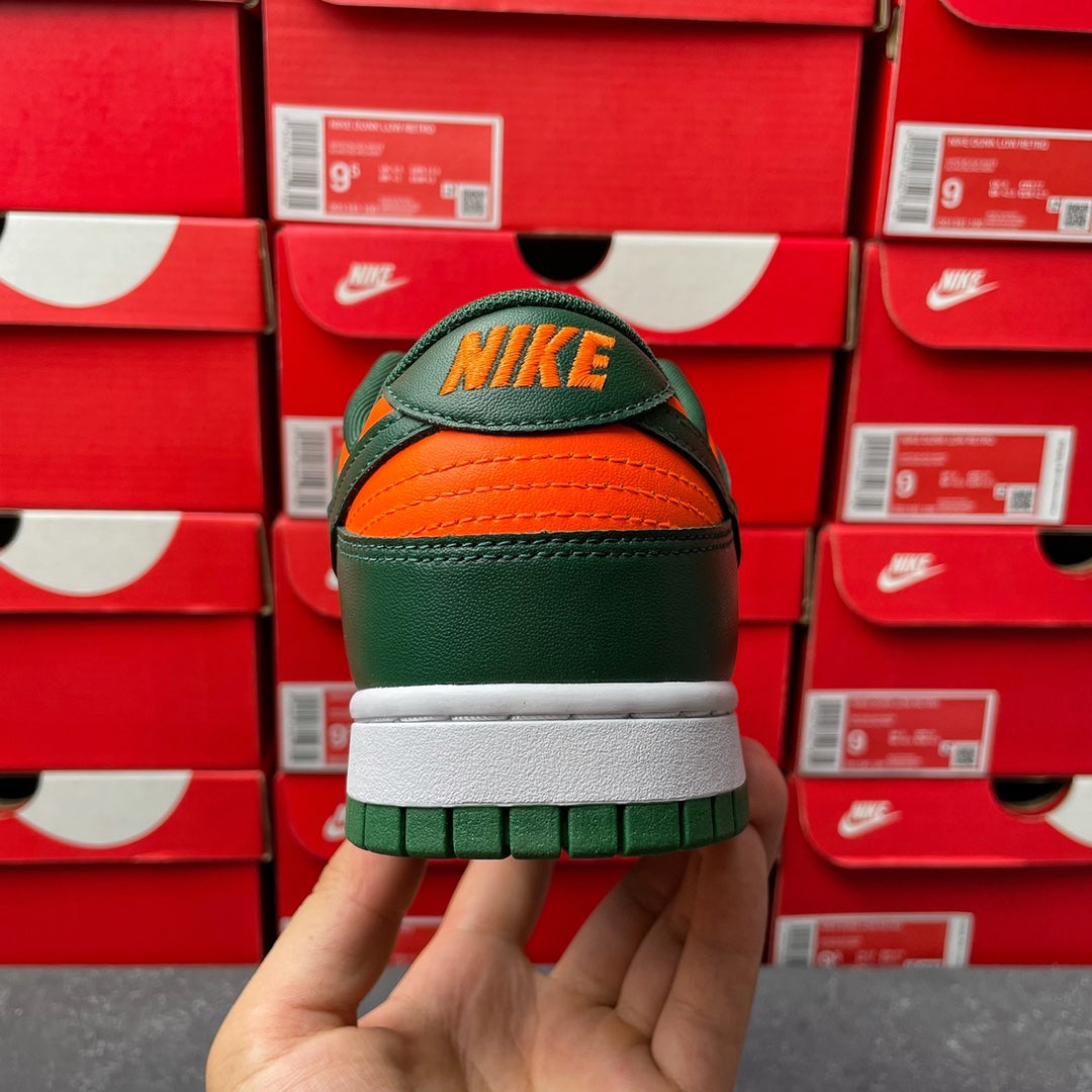 Green low-top sneaker back view with NIKE logo, orange laces, white sole.