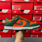 Green and orange low-top sneaker with white sole and black Nike swoosh detail.