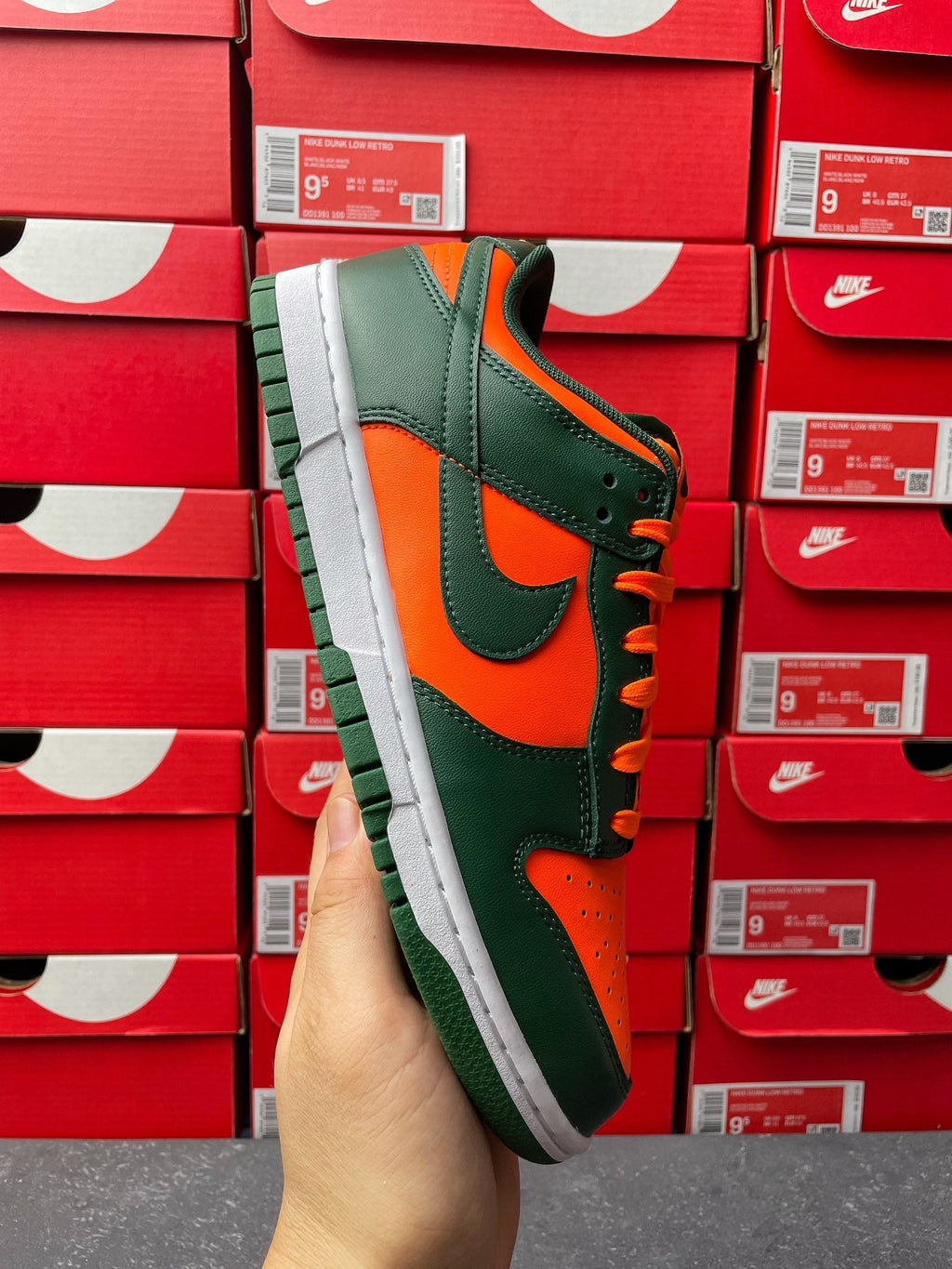 Green and orange low-top sneaker, orange laces, white midsole, black swoosh.