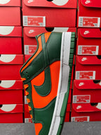 Green and orange low-top sneaker with white midsole and black swoosh, angled view.