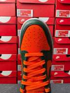 Green toe box low-top sneaker with orange lace-up and perforated forefoot.