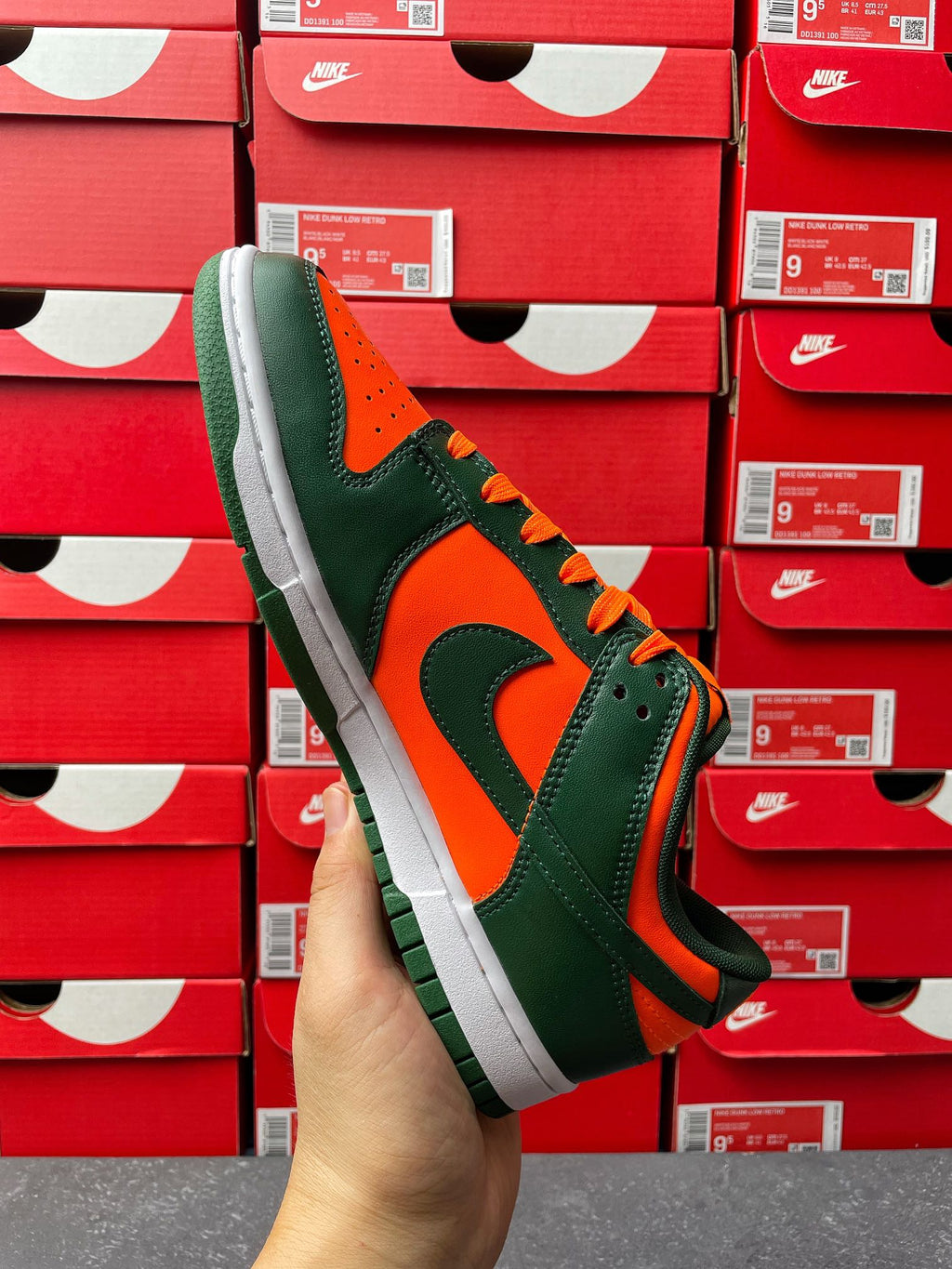 Green and orange low-top sneaker with white midsole and black swoosh, side view.