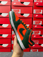 Green and orange low-top sneaker with white midsole and black swoosh, side view.