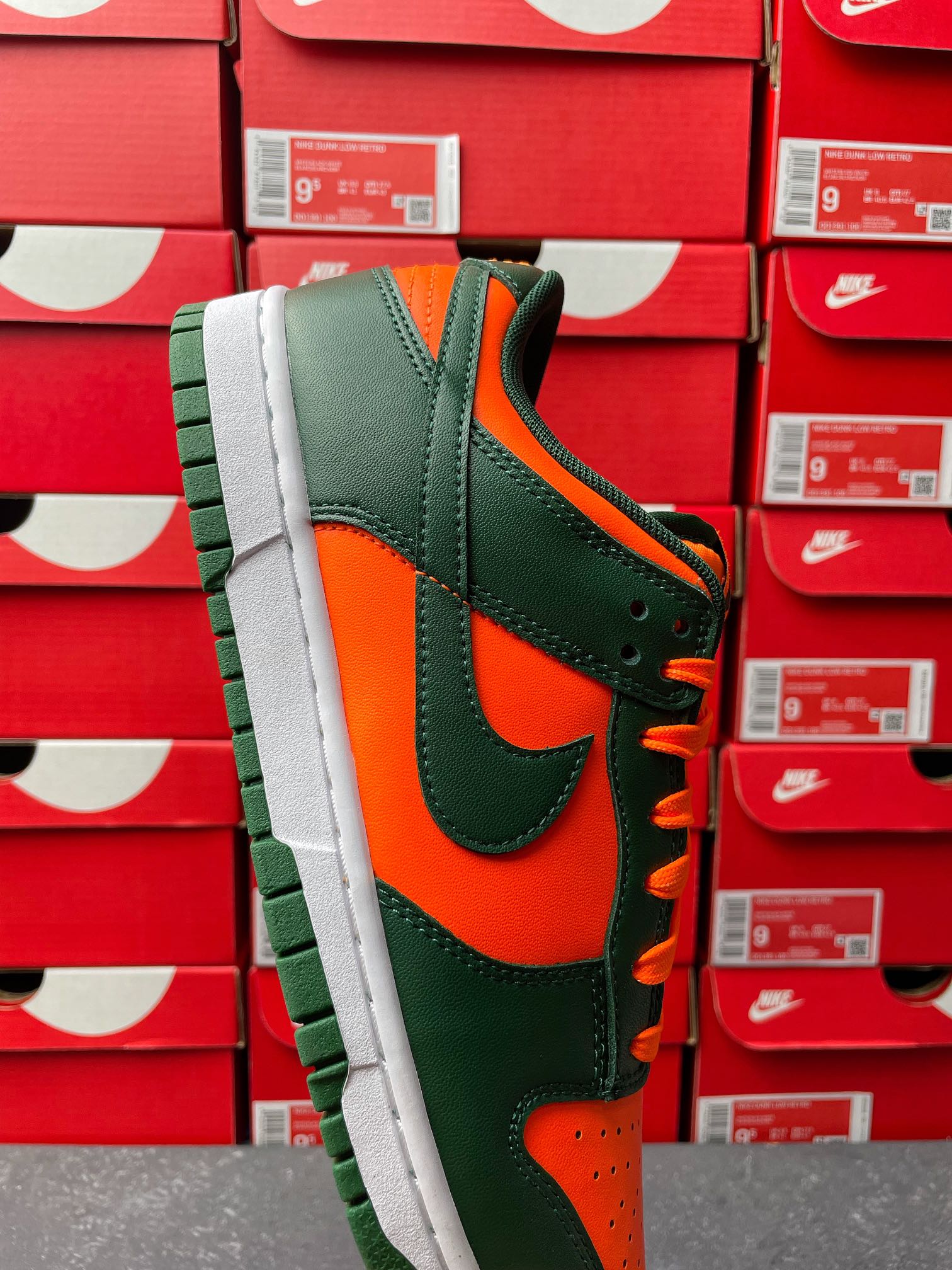 Green leather low-top sneaker with orange overlays and white midsole, side profile.