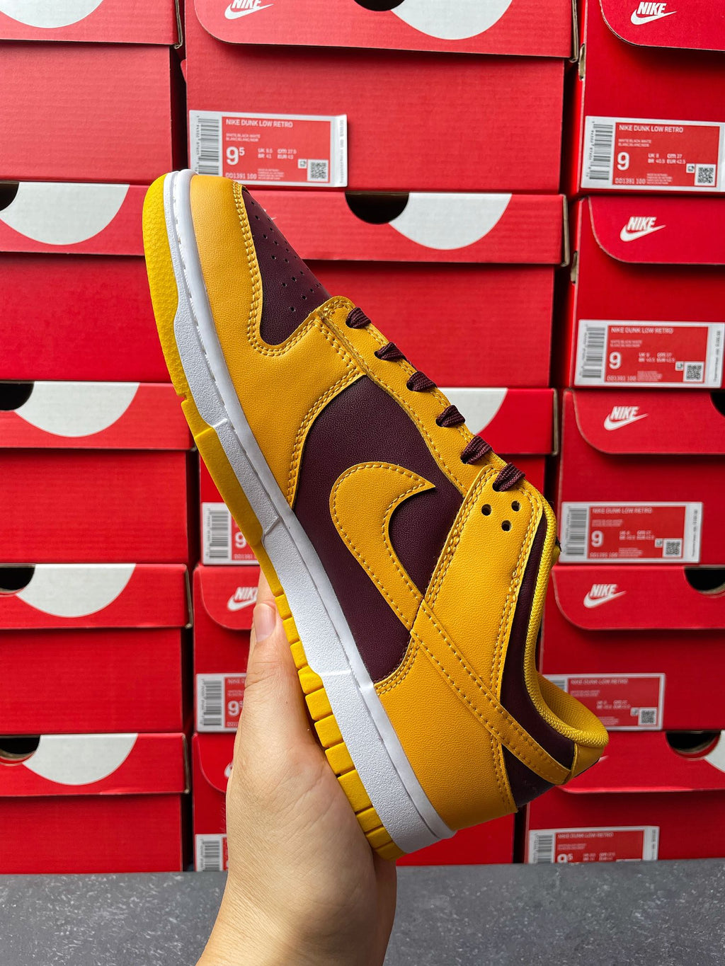 Nike Dunk Low angled view with yellow upper and dark purple side panels on white sole