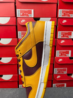 Nike Dunk Low side view showing yellow toe and dark purple swoosh on white sole